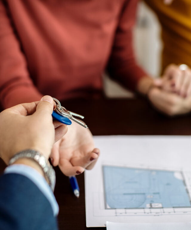 Close-up of real estate agent giving a couple keys of their new Close-up of real estate agent giving a couple keys of their new