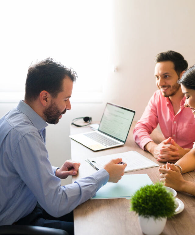Hispanic couple buying flights with a sales agent Hispanic couple buying flights with a sales agent
